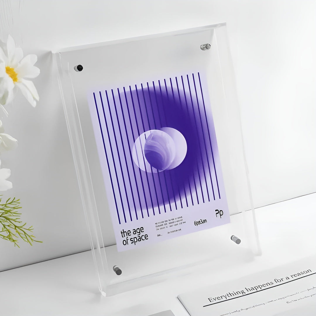 Helt klar akrylramme med beslag, indeholdende et lilla plakatmotiv med lodrette streger og en cirkel, ved siden af hvide blomster. 16
