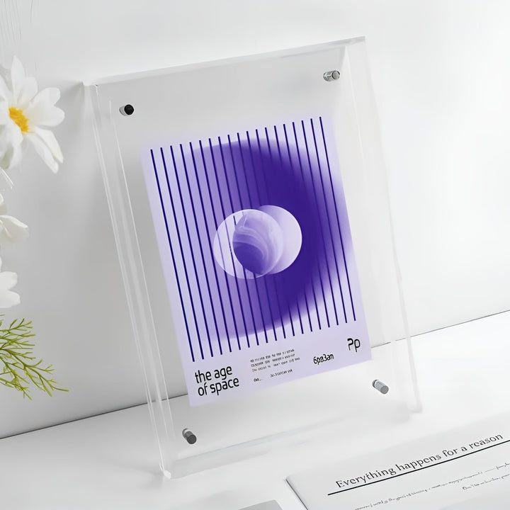 Helt klar akrylramme med beslag, indeholdende et lilla plakatmotiv med lodrette streger og en cirkel, ved siden af hvide blomster. 16