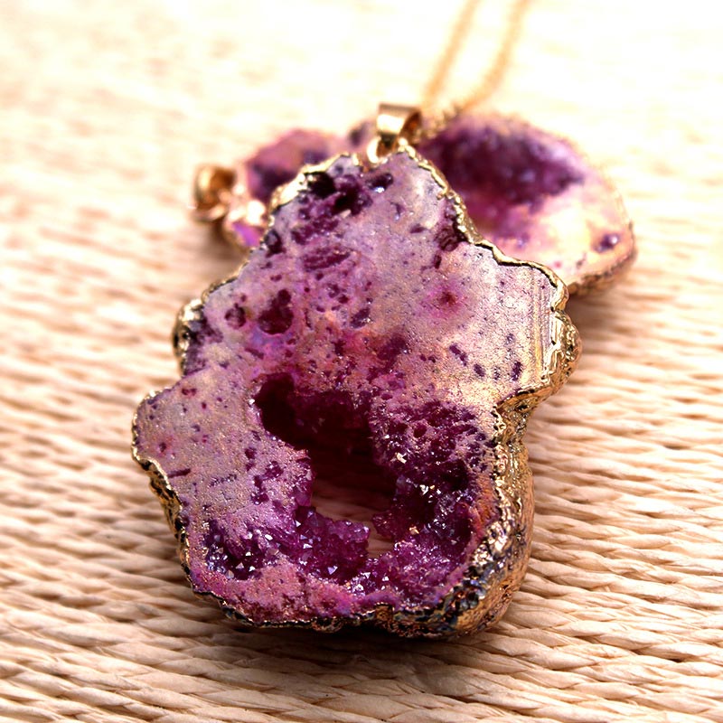 Lila Achat-Anhänger mit goldener Fassung auf geflochtener Oberfläche, Schmuck, Edelstein, elegant.