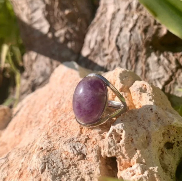 Silberring mit ovalem Amethyst, lila Edelstein, auf Felsen, Schmuck, Naturhintergrund.