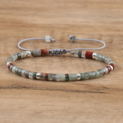 Armband aus Natursteinperlen, grün und rot, verstellbar, handgefertigt, auf Holzoberfläche.