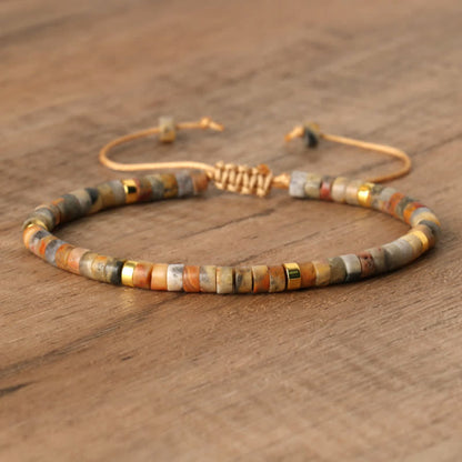 Armband aus Natursteinperlen, verstellbar, beige und gold, handgefertigt, auf Holzoberfläche.