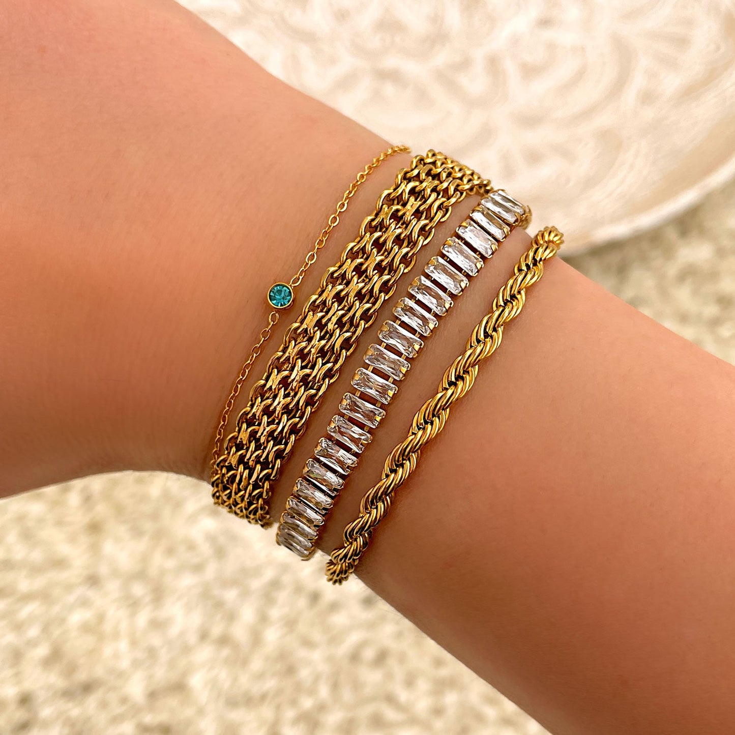 Goldene Armbänder-Set mit Geburtsstein, Zirkonia, geflochtenem Design auf Handgelenk.