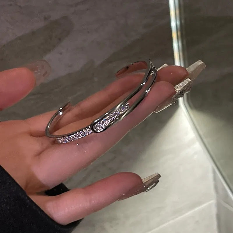 Silbernes Armreif mit Strasssteinen, elegantes Schmuckstück, Damenmode, Accessoire, Nahaufnahme.