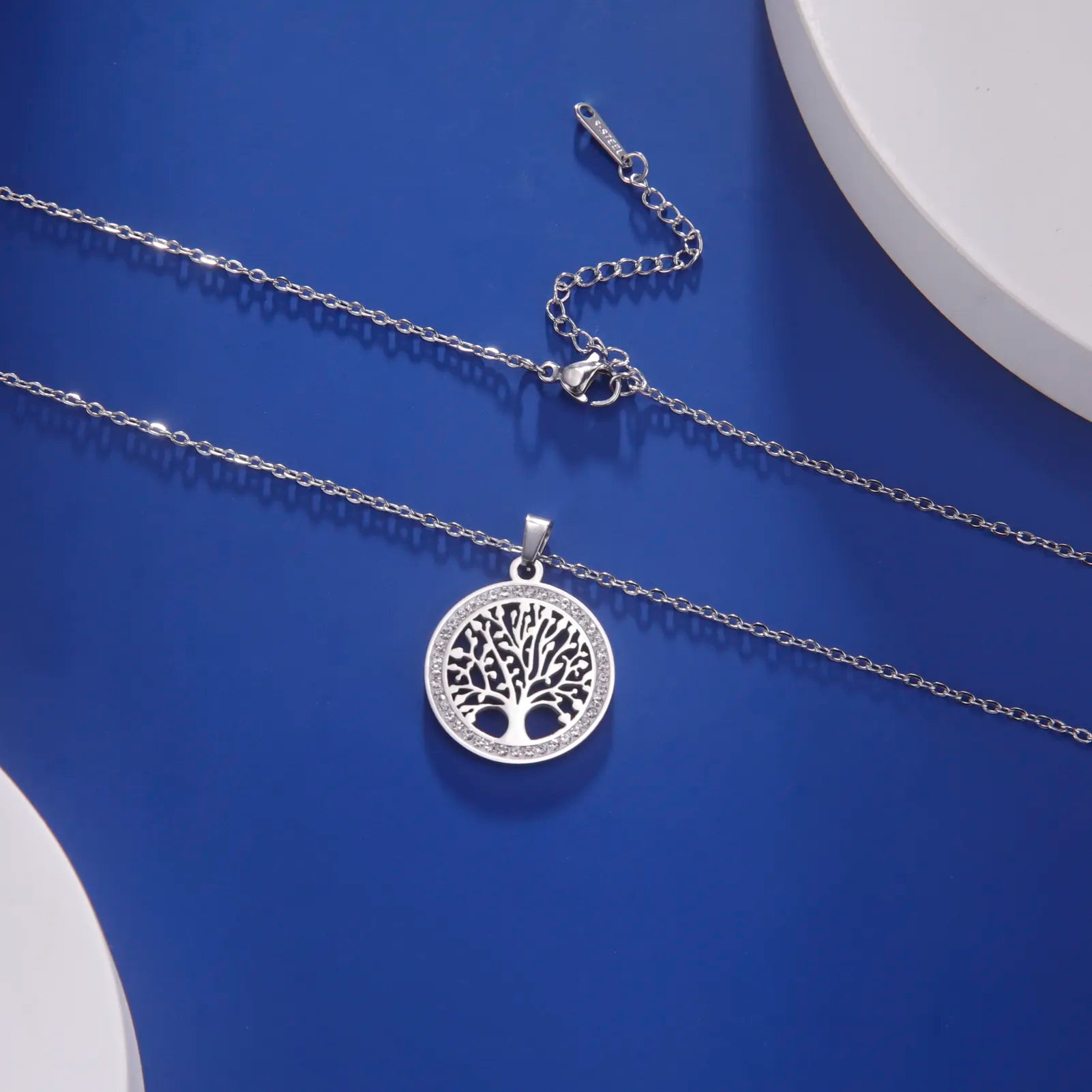 Silberne Lebensbaum-Halskette, filigranes Design, Damen-Schmuck, Geschenkidee, blauer Hintergrund.