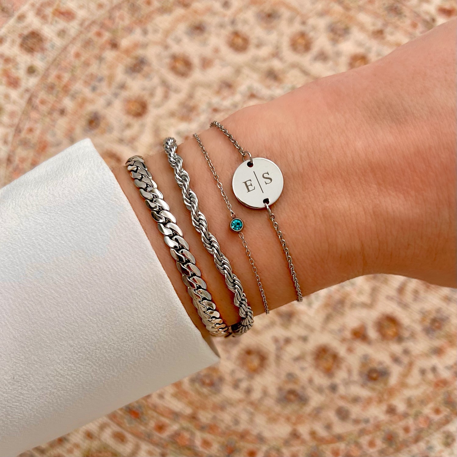 Silberne Armbänder mit Geburtsstein und Gravur auf Handgelenk, modisches Accessoire.