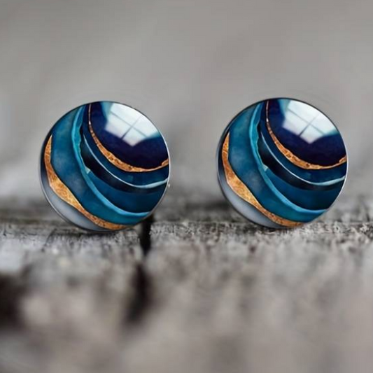 Blaue runde Ohrringe mit goldenen Akzenten auf Holzoberfläche, eleganter Schmuck.