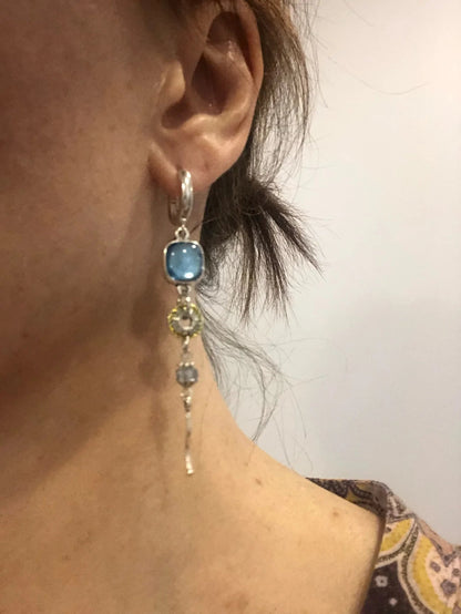 Ohrring mit blauem Stein und silbernen Details, getragen am Ohr einer Frau.