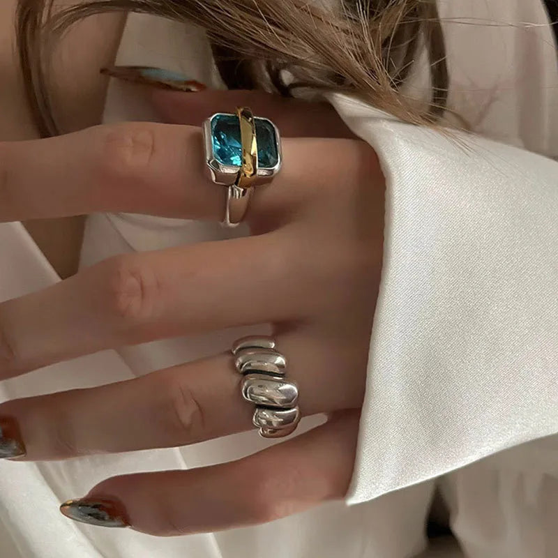 Frau mit silbernem Ring und blauem Edelstein, elegantes Schmuckdesign, Nahaufnahme.