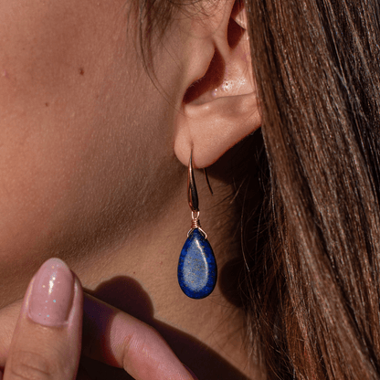 Ohrring mit blauem Tropfen-Anhänger, goldener Haken, eleganter Schmuck, Nahaufnahme.