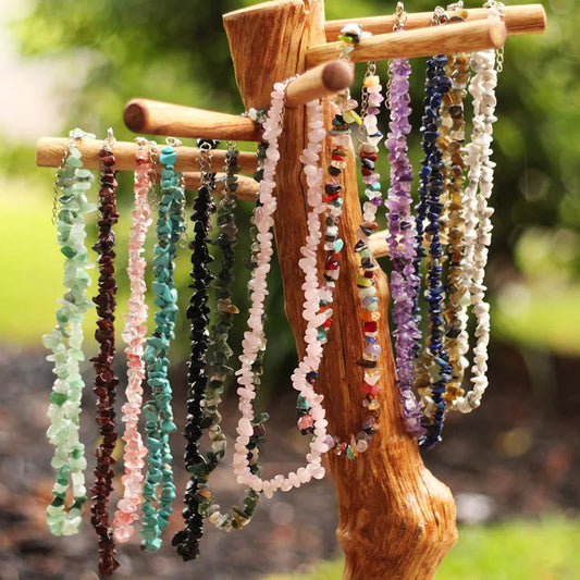 Verschiedene bunte Edelstein-Halsketten an Holzständer im Freien, Schmuck, Natursteine.