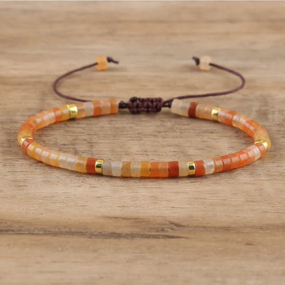 Armband aus bunten Glasperlen, verstellbar, handgefertigt, auf Holzoberfläche.