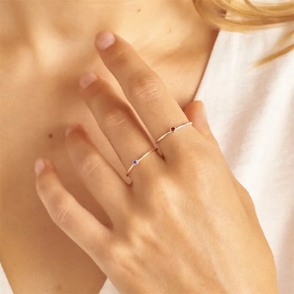 Frau trägt zwei filigrane Goldringe mit blauen und roten Edelsteinen, eleganter Schmuck.