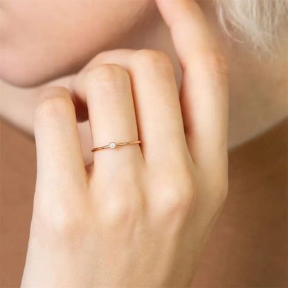 Dünner Goldring mit Diamant an Frauenhand, eleganter Schmuck, minimalistisch, stilvoll.