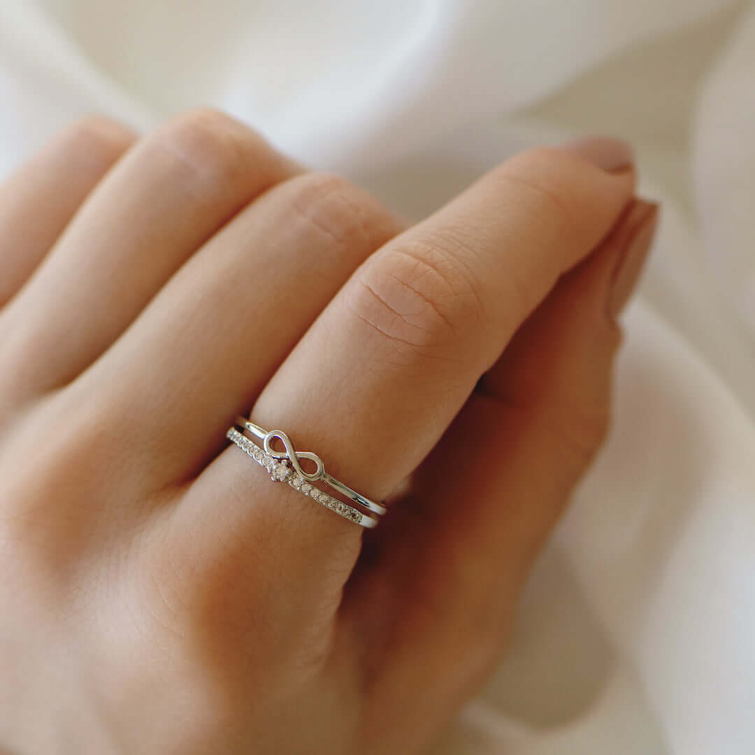 Silberner Unendlichkeitsring mit Diamanten auf Hand, eleganter Schmuck, Verlobungsring.
