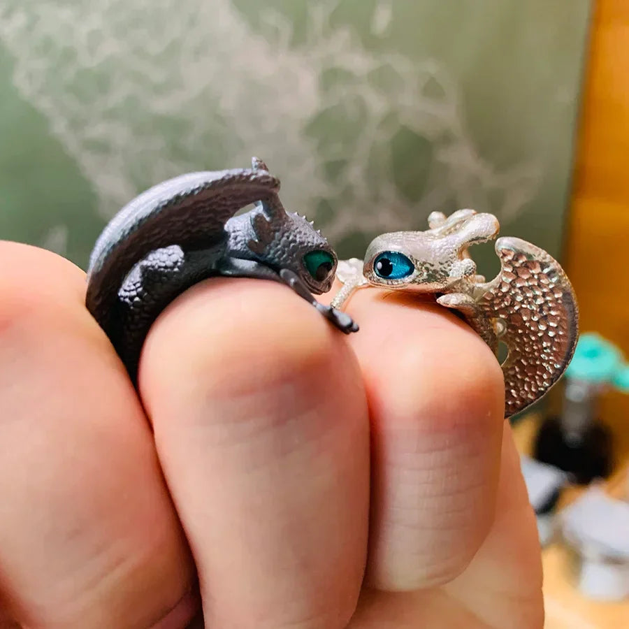 Zwei Eidechsen-Ringe, silber und bronze, mit blauen Augen, auf einer Hand getragen.