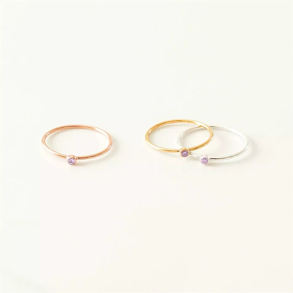 Drei zarte Ringe in Roségold, Gold und Silber mit lila Stein, minimalistischer Schmuck.