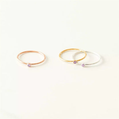 Drei zarte Ringe in Roségold, Gold und Silber mit lila Stein, minimalistischer Schmuck.