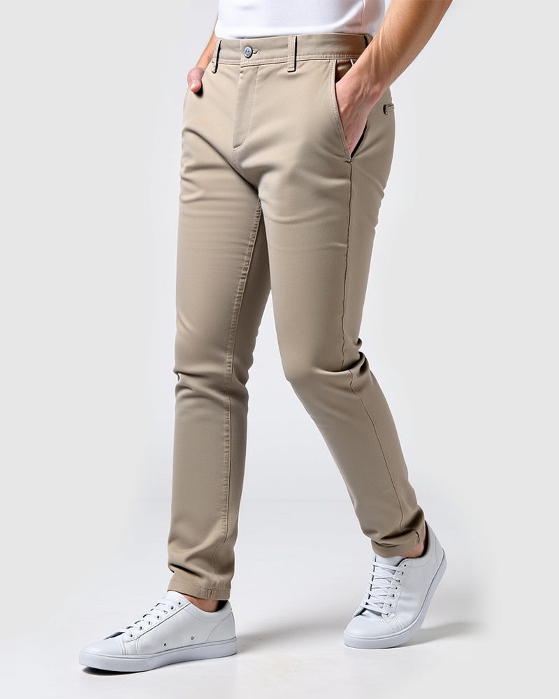 Beige slim fit chinos set fra siden på model med hvid t-shirt, hvide sneakers og hænderne i lommerne. 14