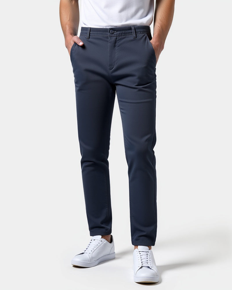 Marineblå slim fit chinos set forfra på model med hvid t-shirt, hvide sneakers og hænderne i lommerne. 15