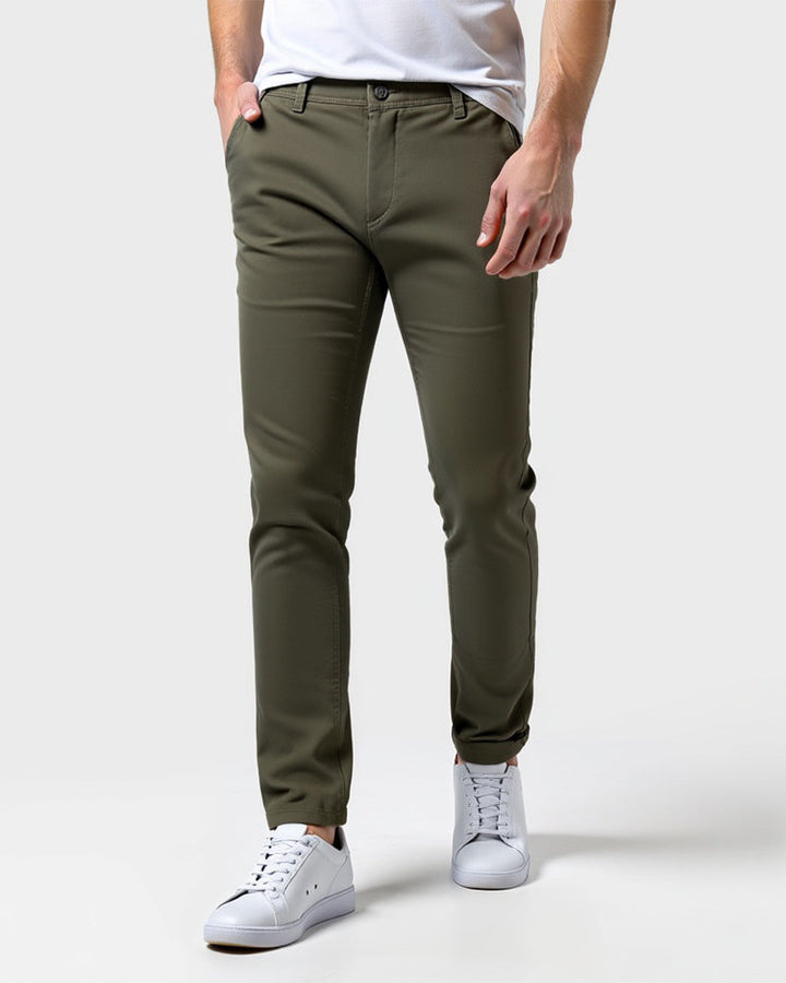 Oliven-grønne slim fit chinos set forfra på model med hvid t-shirt, hvide sneakers og hånden i lommen. 13