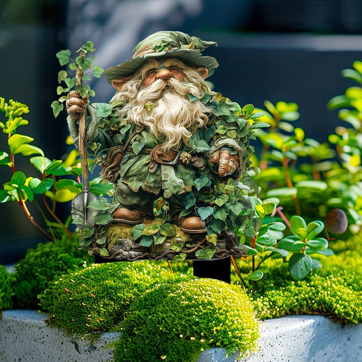 Havetusse med spade og efeubladsdragt, placeret i en betonkumme med tæt mos og små grønne planter. 13