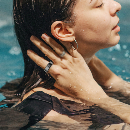 Frau im Wasser mit silbernem Ring und Ohrring, nasses Haar, entspannt, Nahaufnahme.