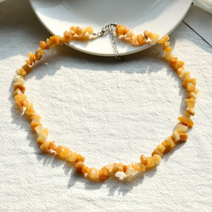 Orange Edelstein-Halskette auf weißem Hintergrund, handgefertigt, modisches Schmuckstück.