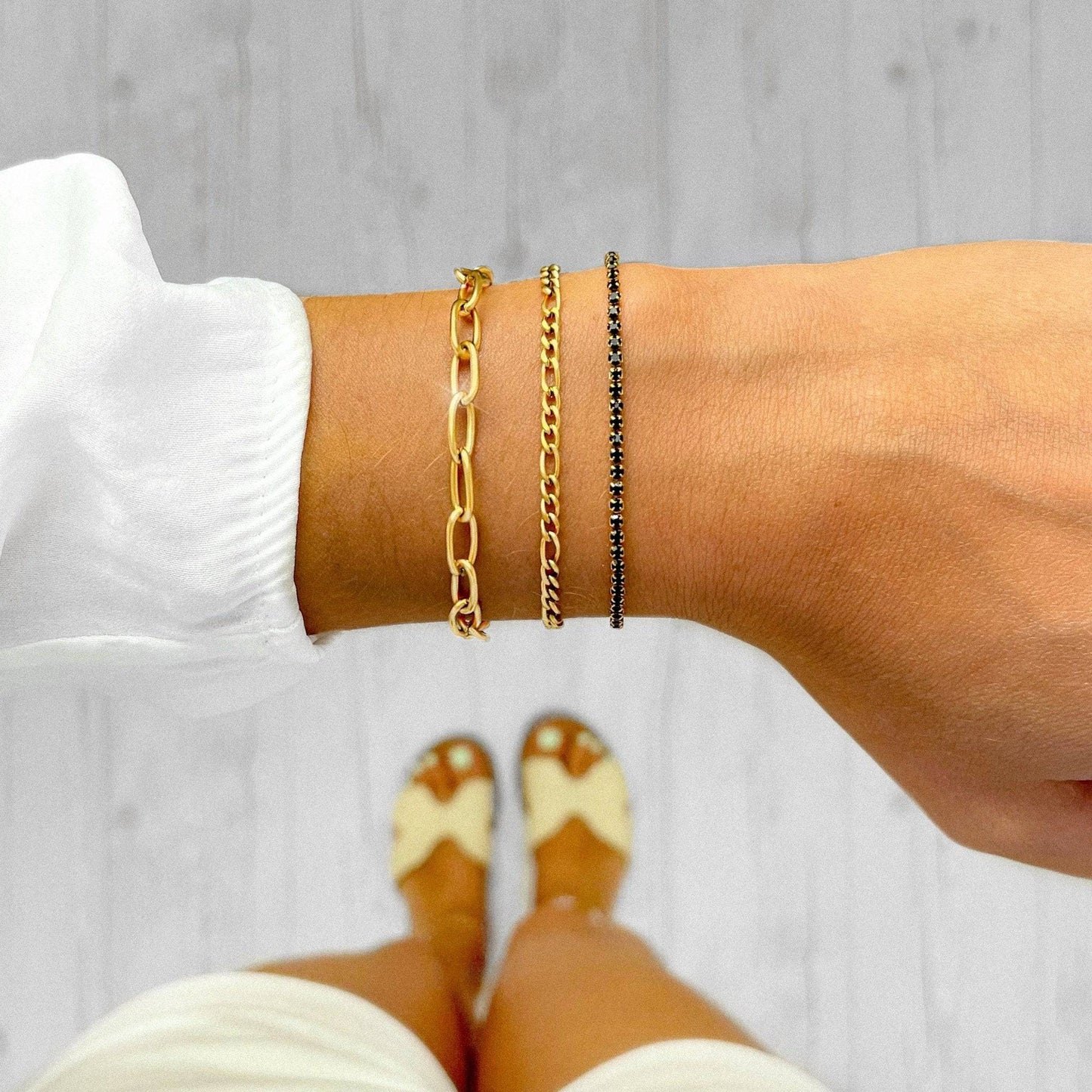 Drei goldene Armbänder am Handgelenk, Gliederarmband, Kettenarmband, Damenmode, Schmuck.