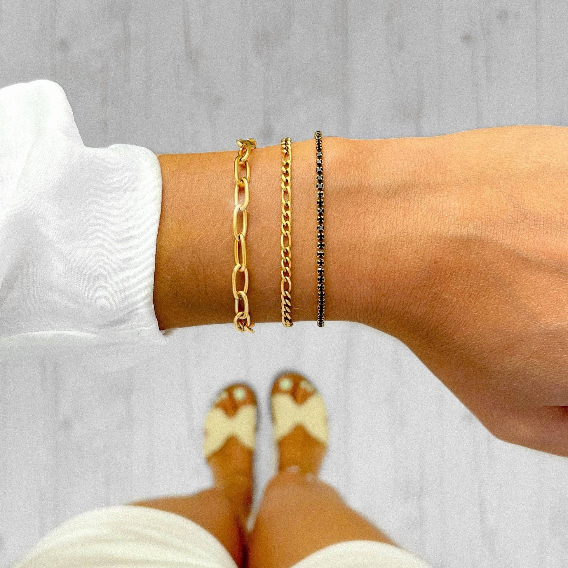 Drei goldene Armbänder am Handgelenk, Gliederarmband, Kettenarmband, Damenmode, Schmuck.