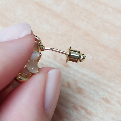 Goldener Ohrring mit Perlen, Nahaufnahme, Hand hält Schmuckstück, elegantes Accessoire.