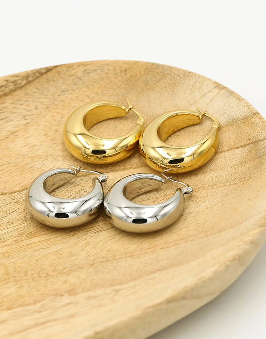 Goldene und silberne Vintage Creolen auf Holztablett, modische Ohrringe, Schmuckaccessoire.