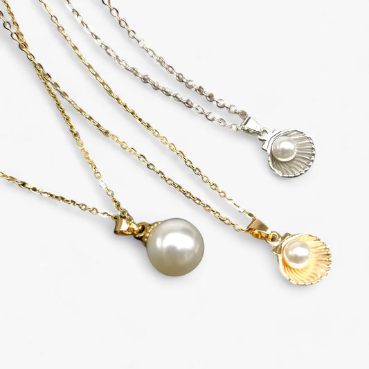 Drei Halsketten mit Perlenanhängern, Gold- und Silberketten, eleganter Schmuck, Nahaufnahme.