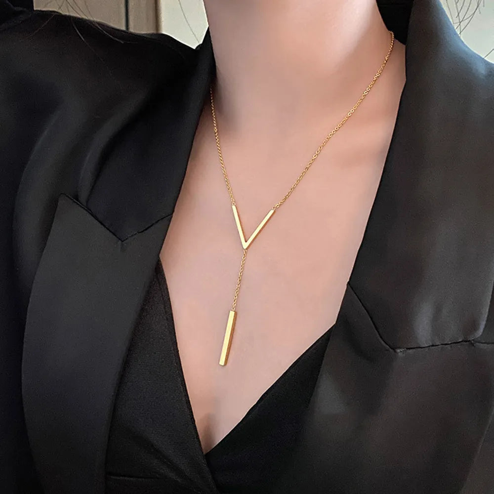 Goldene Y-Halskette, minimalistisches Design, Damenmode, eleganter Schmuck, schwarzes Outfit.