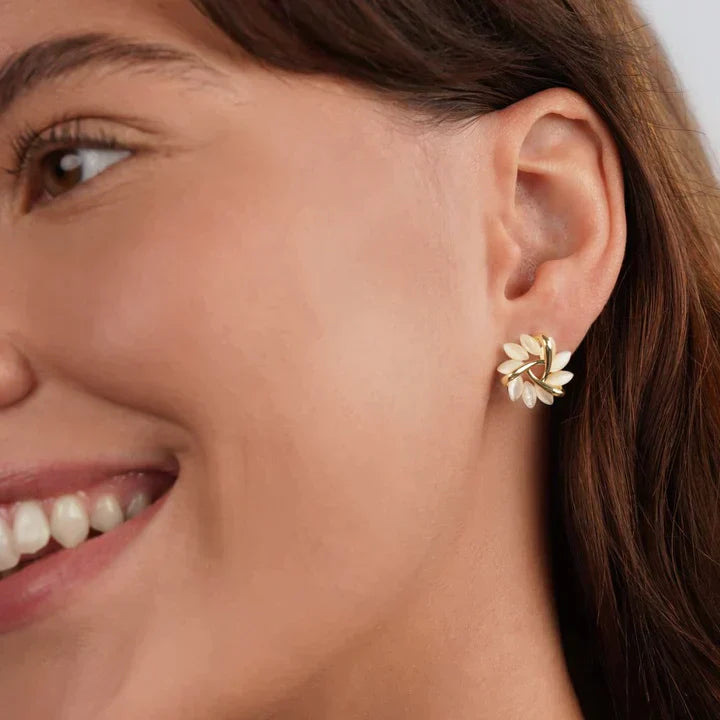 Frau mit goldenen Ohrringen in Blattform, eleganter Schmuck, Nahaufnahme, lächelndes Gesicht.
