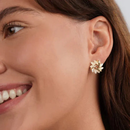 Frau mit goldenen Ohrringen in Blattform, eleganter Schmuck, Nahaufnahme, lächelndes Gesicht.
