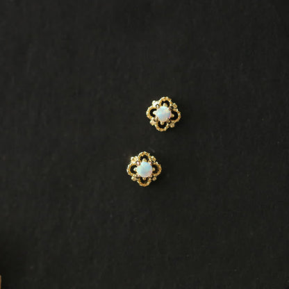 Goldene Ohrringe mit Opal, Blumenform, eleganter Schmuck, Damenaccessoire, schwarzer Hintergrund.