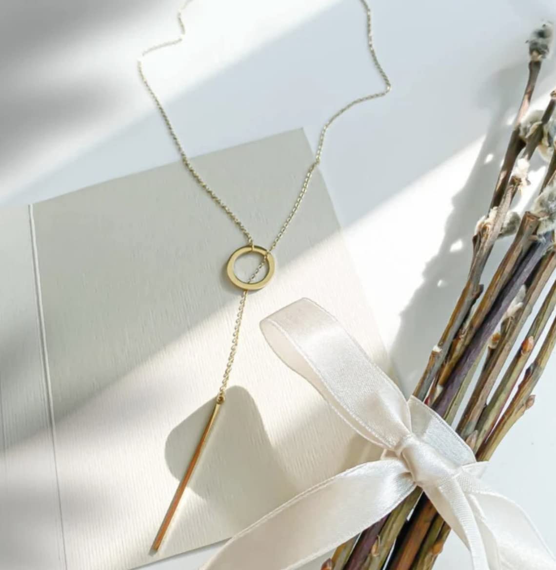 Goldene Halskette mit Kreisanhänger auf weißem Hintergrund, elegantes Schmuckdesign.
