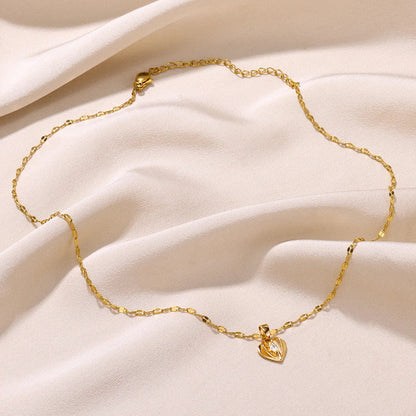 Goldene Halskette mit Herzanhänger auf beigem Stoff, eleganter Schmuck, Damenaccessoire.