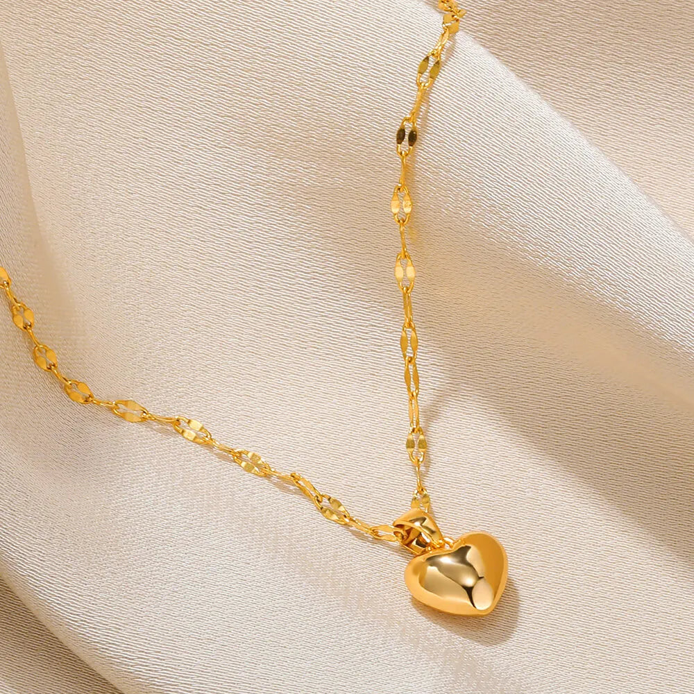 Goldene Herz-Halskette auf beigem Stoff, elegantes Schmuckdesign, Damenaccessoire.
