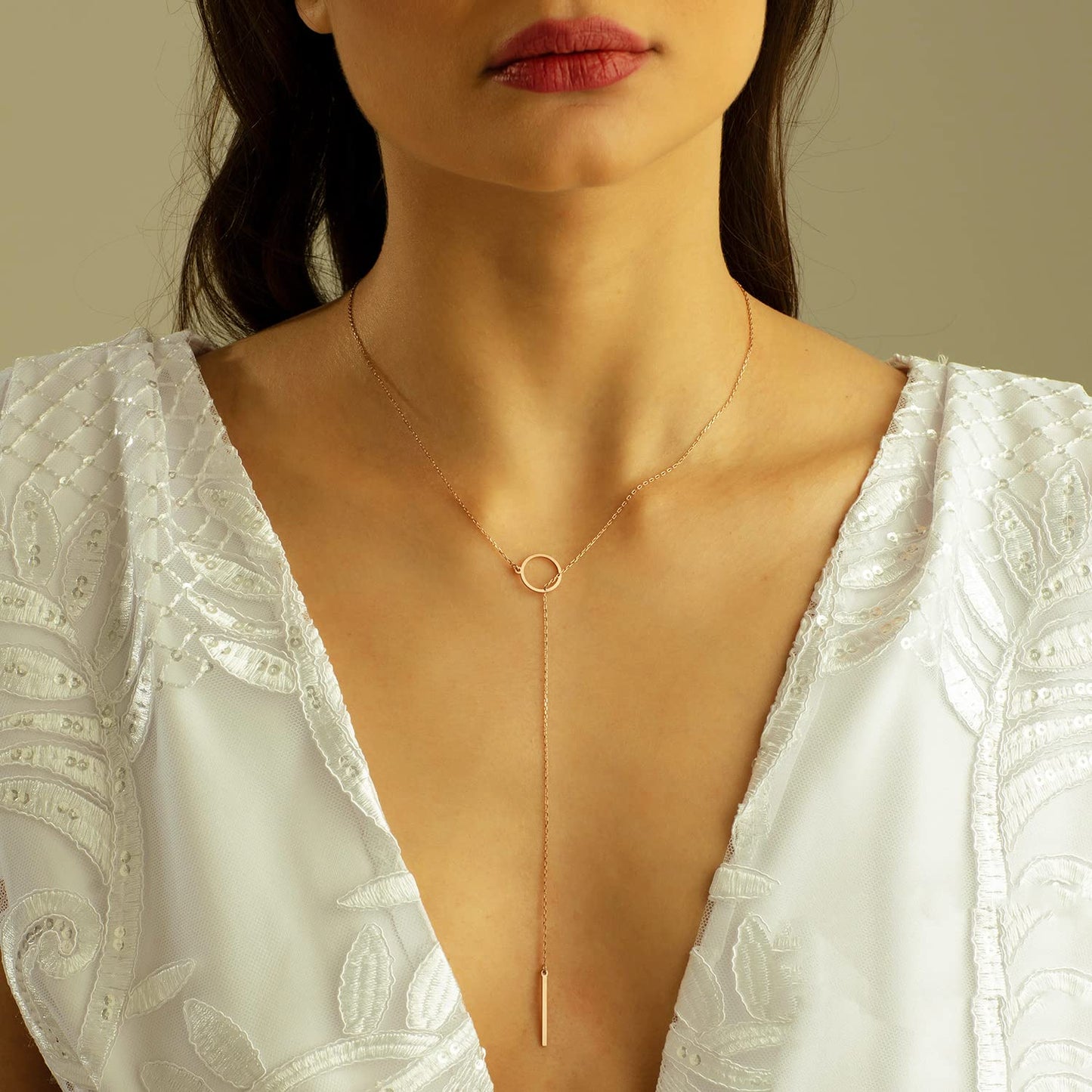 Frau mit elegantem goldenen Y-Halskette, weißes Kleid, Schmuckmode, minimalistisch.