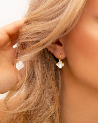 Frau mit goldenen Kleeblatt-Ohrringen, modischer Schmuck, elegantes Design.