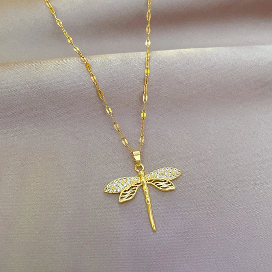 Goldene Libellen-Halskette mit Strasssteinen auf seidigem Hintergrund, eleganter Schmuck.