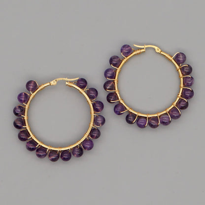 Goldene Creolen mit lila Amethyst-Perlen, handgefertigter Schmuck, elegantes Design.