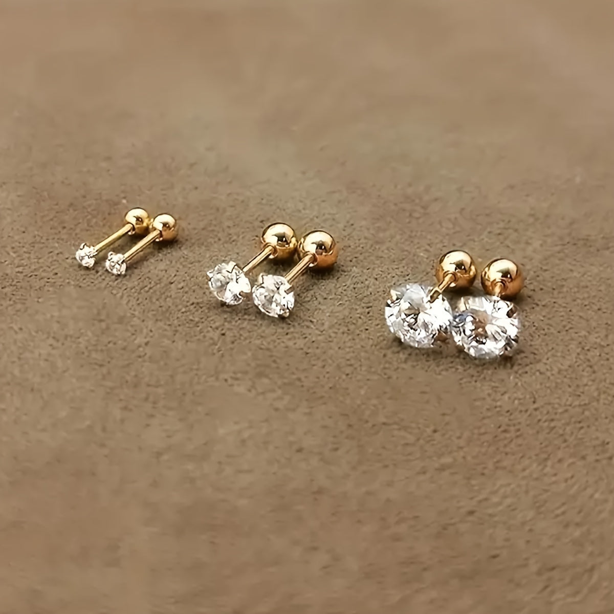Goldene Ohrstecker mit klaren Zirkonia, drei Größen, eleganter Schmuck, glänzend, modisch.