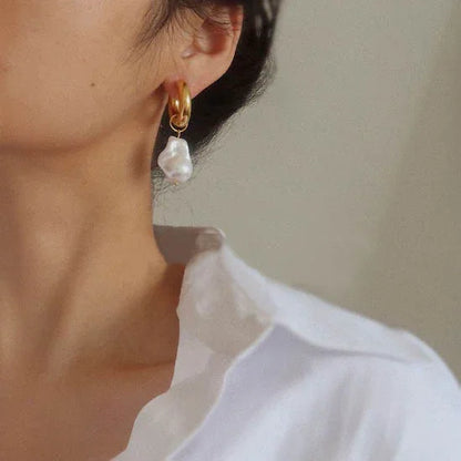 Goldene Creolen mit weißen Perlenanhängern, eleganter Schmuck für Damen, Nahaufnahme.