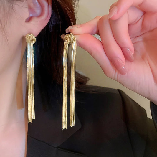 Goldene Quasten-Ohrringe, lang, elegant, Damenmode, Schmuckaccessoire, stilvoll, modern.
