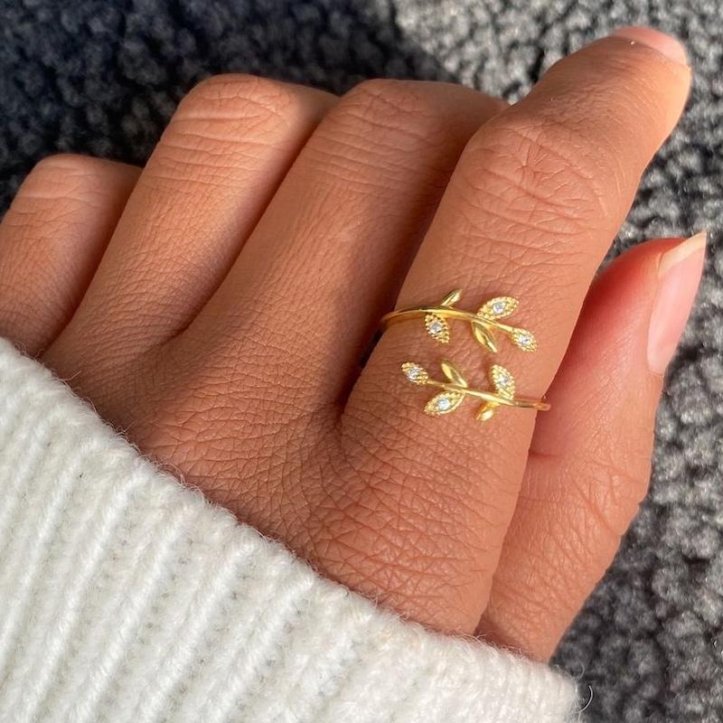 Goldener Blatt-Ring mit Zirkonia-Steinen auf Hand, eleganter Schmuck, Damenmode, Nahaufnahme.