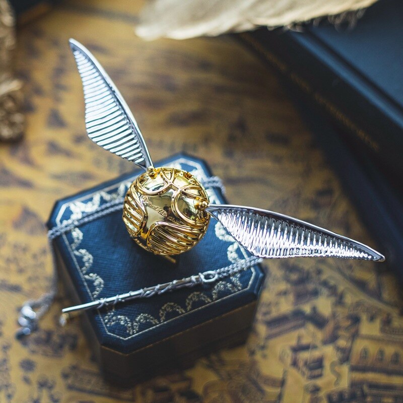 Goldener Schnatz Replik mit silbernen Flügeln auf antikem Hintergrund, Harry Potter Sammlerstück.