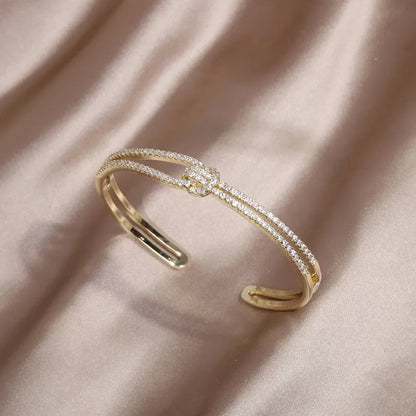 Goldenes Armreif mit Diamanten auf Seidenstoff, elegantes Schmuckdesign, luxuriöses Accessoire.